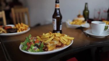 Eggs Benedict with Salad and Fries on a Wooden Table