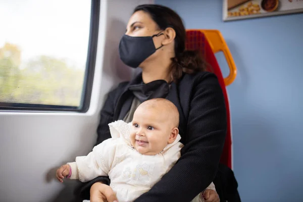 Mulher olhando pela janela de um ônibus e segurando seu bebê sorridente — Fotografia de Stock