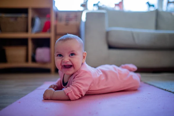 Sorrindo bebê menina deitada em um tapete rosa — Fotografia de Stock