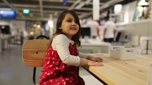 Cheerful Little Girl in a Red Dress Sitting on a Wooden Rotating Chair — Stok video