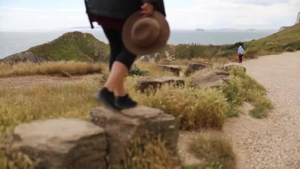 Woman Walking on Big Rocks with the Jurassic Coast as Background — Vídeo de Stock