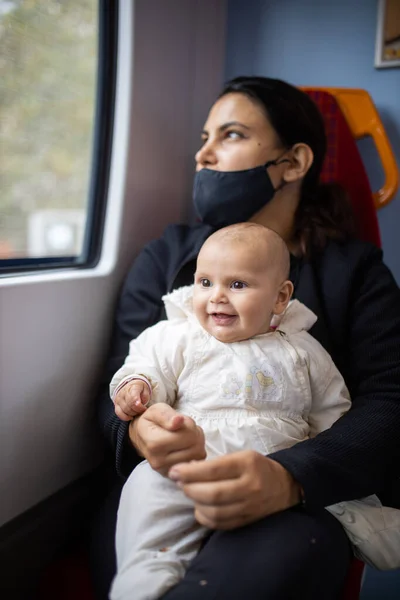 Mulher olhando pela janela de um ônibus e segurando seu bebê sorridente — Fotografia de Stock