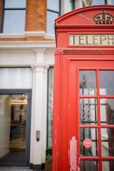 Vista Retrato de uma cabine telefônica de Londres e um prédio branco atrás dela — Fotografia de Stock