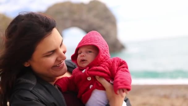 Mother Holding and Kissing her Baby with the Durdle Door as Background — ストック動画