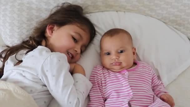 Niña descansando en una cama con su hermana bebé feliz — Vídeos de Stock