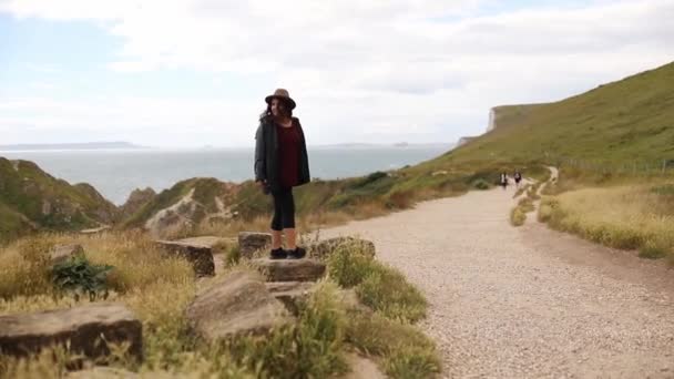 Woman Standing on a Big Rock with the Jurassic Coast as Background — Vídeo de Stock