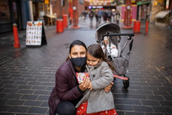 Mulher e sua filhinha em um beco de Chinatown com um carrinho atrás — Fotografia de Stock