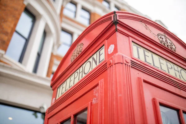 Feche o topo de uma cabine telefônica de Londres e um prédio de tijolos atrás dela — Fotografia de Stock