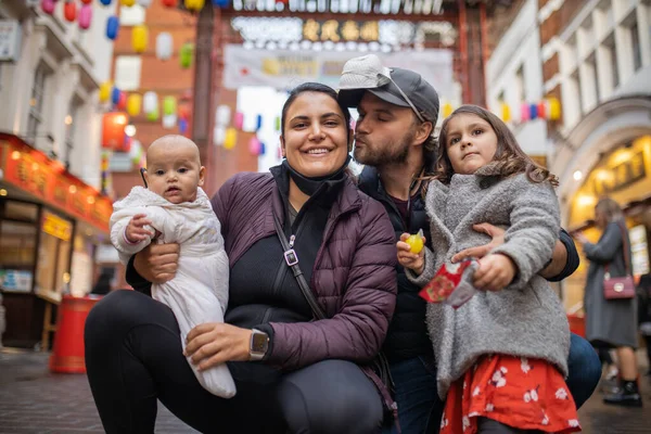 Dwoje szczęśliwych rodziców i ich dwie córki pozujące w zamglonej alejce Chinatown — Zdjęcie stockowe