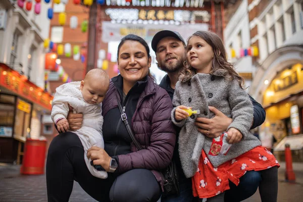 Dwoje szczęśliwych rodziców i ich dwie córki pozujące w zamglonej alejce Chinatown — Zdjęcie stockowe