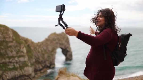 Woman Recording Herself and the Durdle Door During a Windy Day — Wideo stockowe