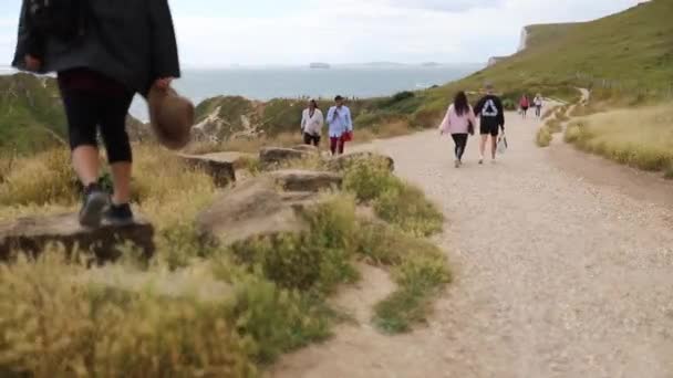 쥬라기 코스트 에서 배경으로 큰 바위 위를 걷는 여자 — 비디오