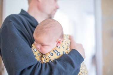 Büyükbabasının kollarında sarı tulum giyen Uyuyan Bebek Kız.