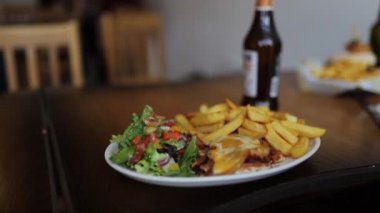 Eggs Benedict with Salad and Fries on a Wooden Table