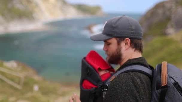 Homem com seu bebê aprecia a vista da costa jurássica — Vídeo de Stock