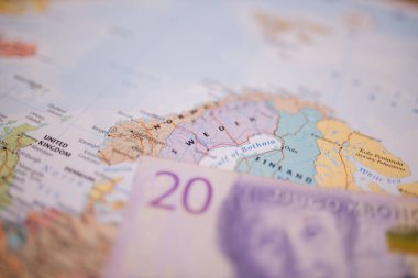 Twenty Swedish kronor bill below Sweden on a colorful and blurry Europe map