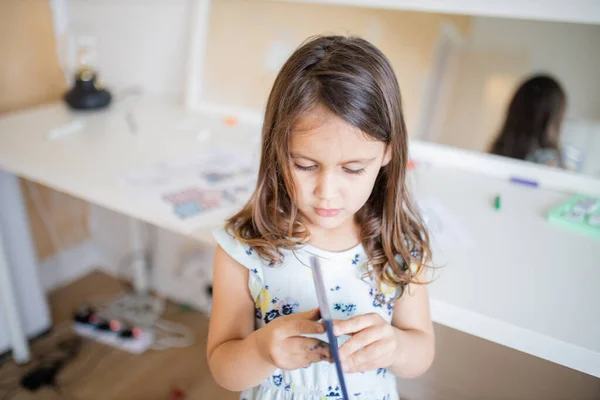 Little girl looking at an American passport with a desk and a mirror behind her — Stock fotografie