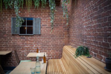Wooden tables and seats surrounded by the red brick walls of a vegan restaurant
