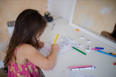 Little girl coloring an image of the Statue of Liberty with a yellow pencil