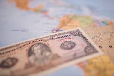 Five sucres bill below Ecuador on a colorful and blurry map of South America