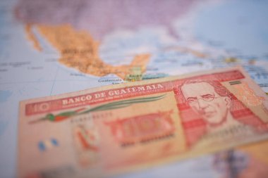 Ten quetzales bill below Guatemala on a colorful and blurry map of America