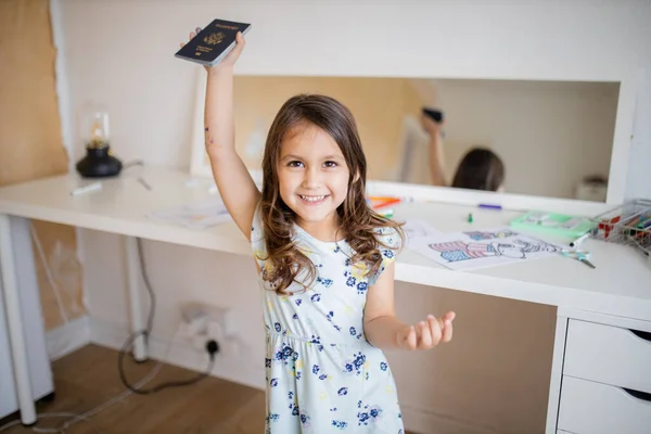 Mała dziewczynka przed biurkiem, podnosząca amerykański paszport wysoko ponad głowę. — Zdjęcie stockowe