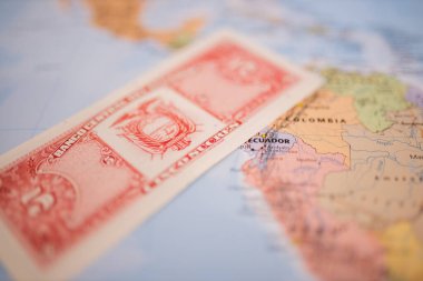 Five sucres bill below Ecuador on a colorful and blurry map of South America