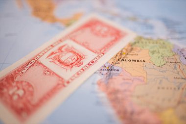 Five sucres bill next to Ecuador on a colorful and blurry map of South America