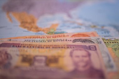 Bills of one, five, and two lempiras below Honduras on a blurry America map