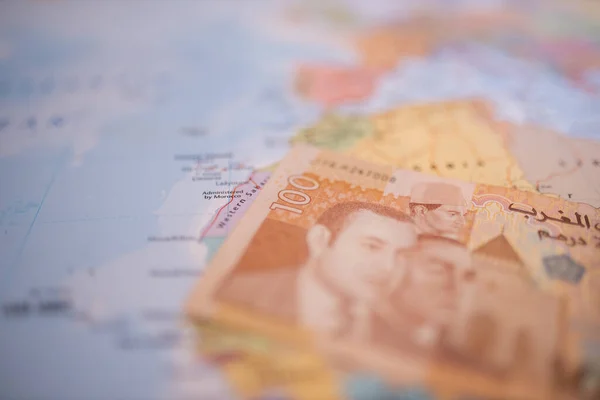 One hundred Moroccan dirham bill below Morocco on a colorful and blurry map