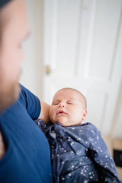 Mała dziewczynka śpi w jej niebieski Onesie podczas gdy tata podziwia ją — Zdjęcie stockowe