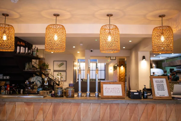 Wooden counter of a vegan restaurant with four lamps hanging above it — Foto Stock