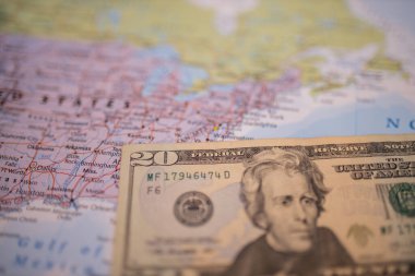 Twenty-dollar bill next to The United States of America on a colorful map