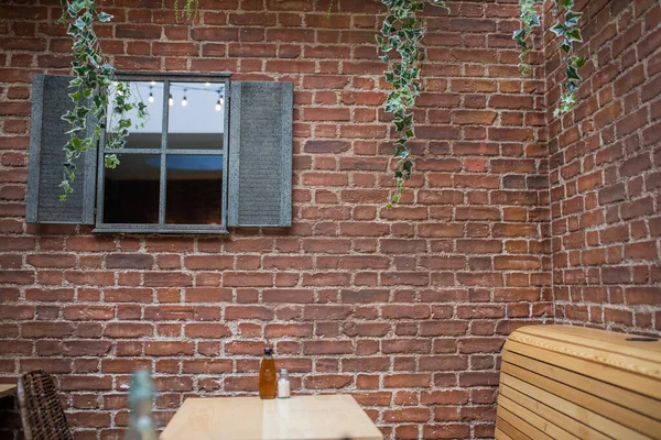 Window on a red bricks wall with a table and wooden seats at the bottom — Photo