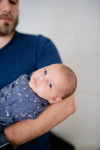 Baby Girl is Looking Concerned in Her Blue Onesie While dad looks on