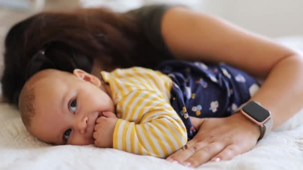 Mama îmbrățișează și sărută copilul ei fericit care are mâinile în gură — Videoclip de stoc