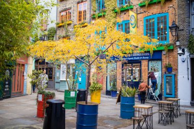 Trees and plants on colorful steel barrels outside a red brick cafe shop