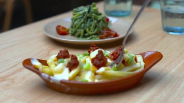 Gabel auf einem luftgebratenen Fritten und getrockneten Tomaten Gericht auf einem Holztisch — Stockvideo