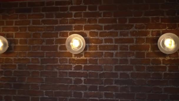 Three lights on a red brick wall from the interiors of a vegan restaurant — Stock Video