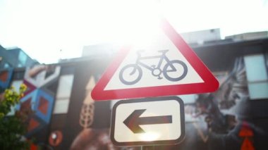 A Triangular Bicycle Sign with a Colorful Mural in the Background