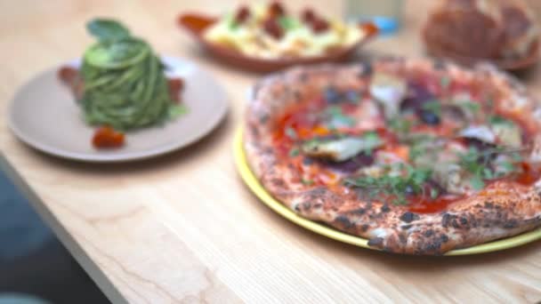 Vegan pizza, fries, zucchini noodles, and cheesy dough balls on a wooden table — Stock Video