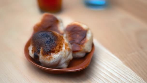 Cheesy dough balls alongside a glass of water and a bottle on a wooden table — Stockvideo