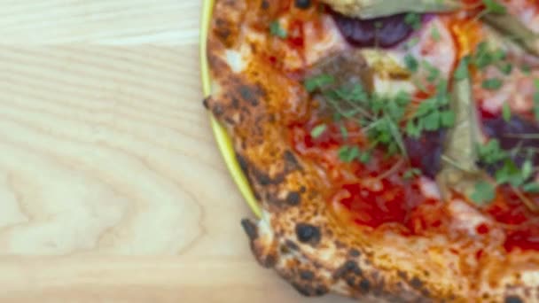 Ascending view above a vegan pizza and a frothy beverage on a wooden table — Stock Video