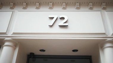 Girişin yukarısındaki beyaz binada 72 numaralı adres.