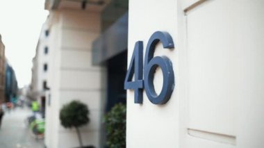 Address number 46 on a wall next to the entrance of a white building
