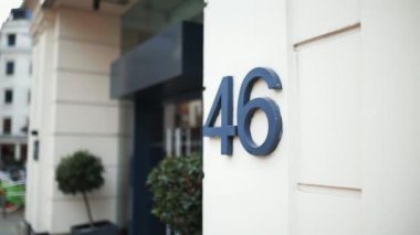 Address number 46 on a wall next to the entrance of a white building