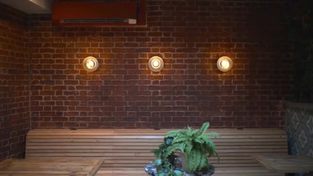 Tables, chairs, and three lights on a red brick wall from a vegan restaurant — Wideo stockowe