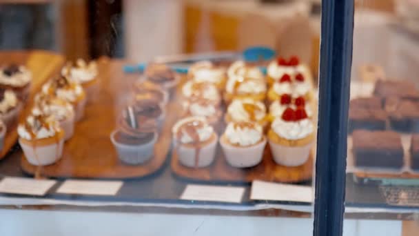Coklat berwarna dan cupcakes raspberry melalui jendela toko roti — Stok Video