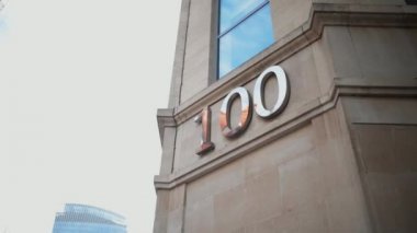 Gri bir binanın köşesindeki pencerenin altında 100 numaralı adres.