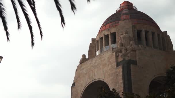 Monumentet till revolutionen bakom vissa träd och under en mycket molnig himmel — Stockvideo